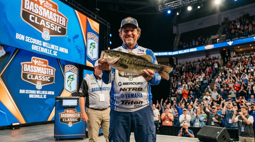 Professional bass angler holding a largemouth bass during the Bassmaster Classic tournament weigh-in at Bon Secours Wellness Arena Greenville