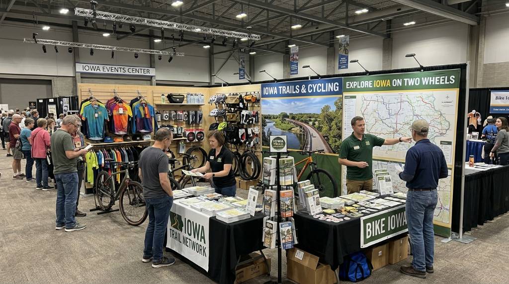 Exhibitor booth with trail maps and cycling gear at the Iowa Events Center